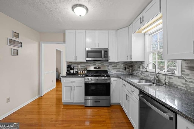 1417 Hickory Dr SW, Lilburn, GA 30047 - kitchen with appliances with stainless steel finishes, backsplash, white cabinets, dark stone counters, and a textured ceiling