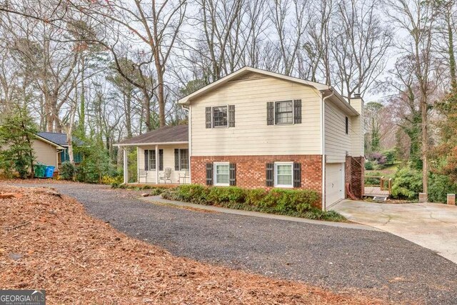 1417 Hickory Dr SW, Lilburn, GA 30047 - split level home featuring driveway, brick siding, an attached garage, and a chimney
