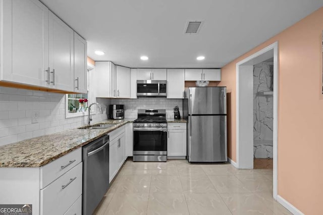 1417 Hickory Dr SW, Lilburn, GA 30047 - kitchen featuring appliances with stainless steel finishes, white cabinets, light stone countertops, backsplash, and recessed lighting