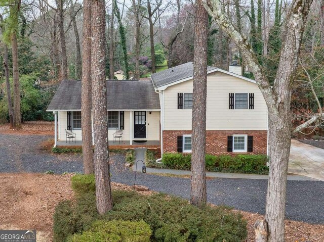 1417 Hickory Dr SW, Lilburn, GA 30047 - split level home with a chimney, brick siding, and a porch