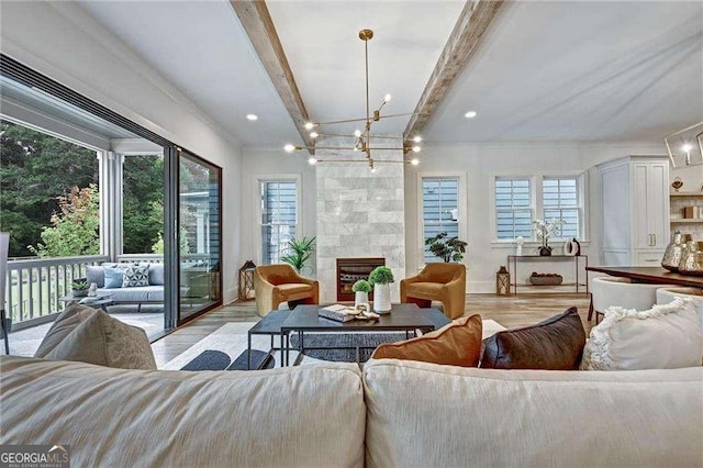 living area featuring a notable chandelier, beam ceiling, a fireplace, light wood-style flooring, and recessed lighting