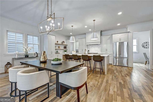 dining room featuring baseboards, a notable chandelier, crown molding, and light wood-style floors