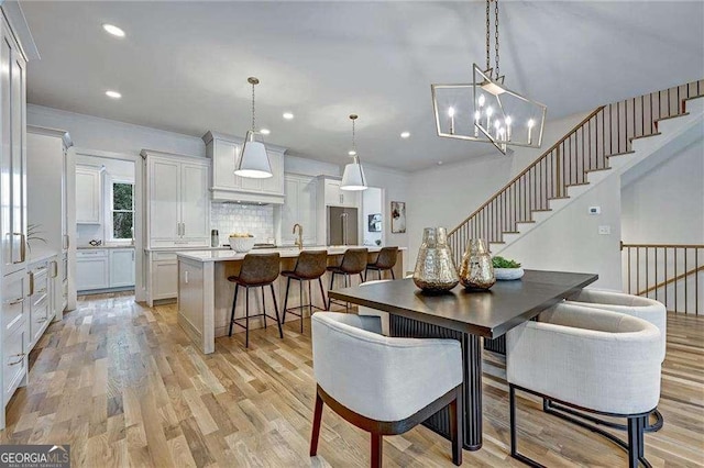 dining area with stairway, recessed lighting, a chandelier, and light wood-style floors