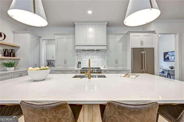 kitchen featuring a large island with sink, tasteful backsplash, crown molding, open shelves, and high quality fridge