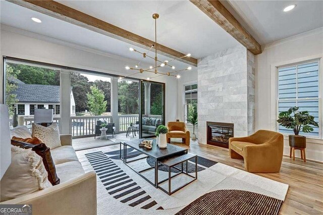 living room with a notable chandelier, wood finished floors, beamed ceiling, and plenty of natural light