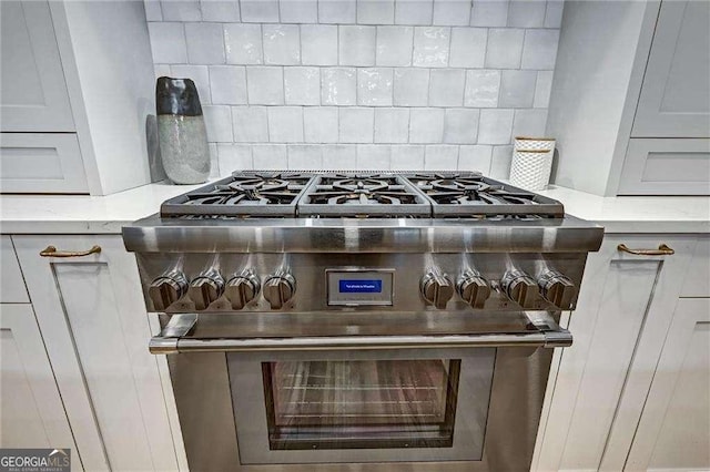 room details featuring light countertops, decorative backsplash, and stainless steel stove