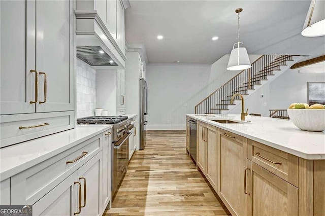 kitchen featuring light countertops, a sink, premium range hood, light wood-style flooring, and stainless steel appliances