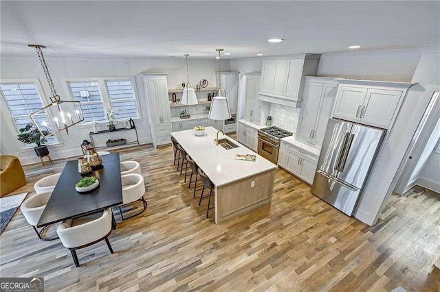 kitchen featuring tasteful backsplash, a breakfast bar area, light wood-type flooring, a sink, and premium appliances