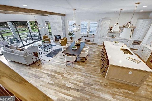 living area featuring a healthy amount of sunlight, a tile fireplace, light wood-style floors, and a chandelier