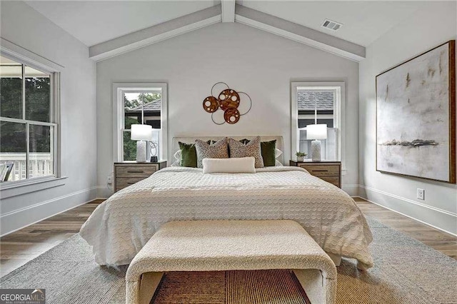 bedroom with baseboards, visible vents, wood finished floors, and lofted ceiling with beams