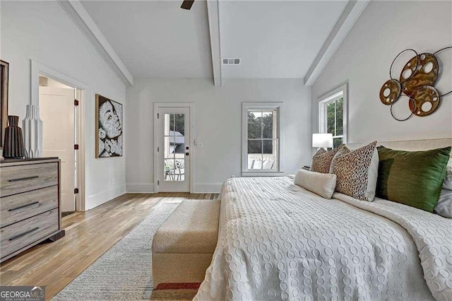bedroom with multiple windows, visible vents, beam ceiling, and light wood-type flooring