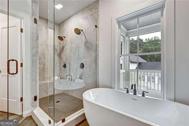 full bath with a wealth of natural light, a freestanding tub, and a shower stall