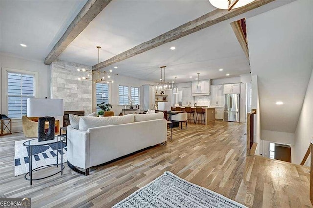 living area featuring light wood-type flooring, beam ceiling, recessed lighting, and a chandelier