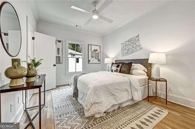 bedroom with ornamental molding, visible vents, and light wood finished floors
