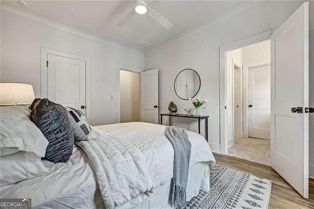 bedroom featuring light wood-style flooring, ornamental molding, and ceiling fan