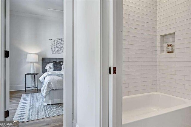 ensuite bathroom featuring baseboards, connected bathroom, and wood finished floors