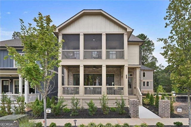 view of side of home featuring covered porch, board and batten siding, and brick siding