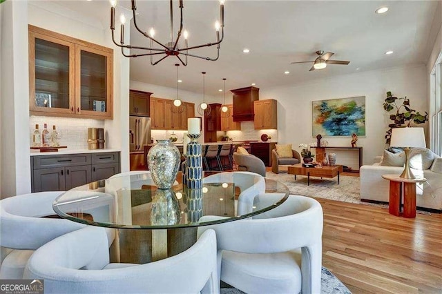 dining room featuring light wood-style flooring, ceiling fan with notable chandelier, and recessed lighting