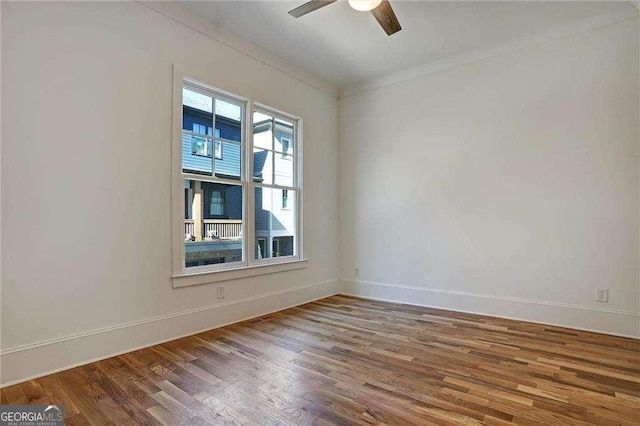 empty room featuring baseboards, crown molding, wood finished floors, and ceiling fan