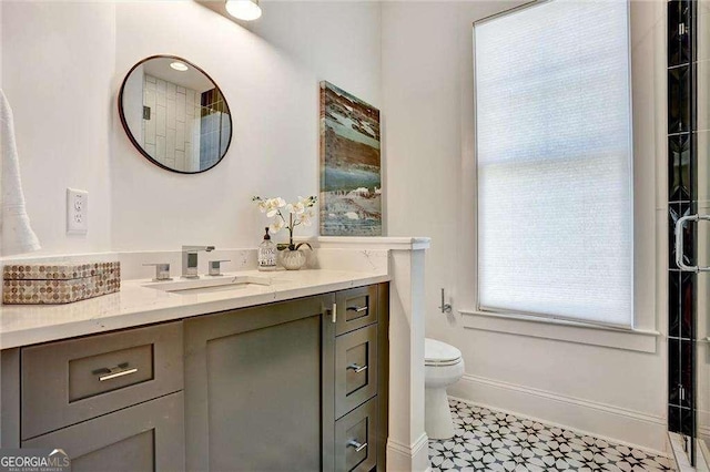 bathroom featuring toilet, vanity, and baseboards