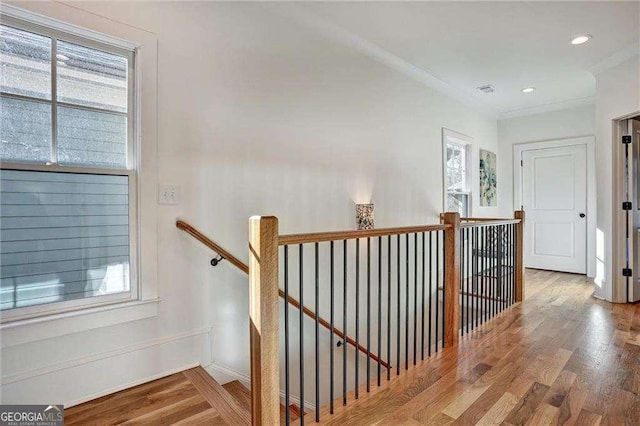 stairs with recessed lighting, ornamental molding, a healthy amount of sunlight, and wood finished floors