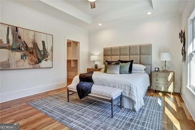 bedroom with baseboards, wood finished floors, recessed lighting, and a raised ceiling