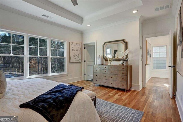 bedroom featuring wood finished floors, baseboards, a raised ceiling, and visible vents