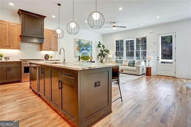 kitchen with a ceiling fan, a sink, ornamental molding, and light wood-type flooring