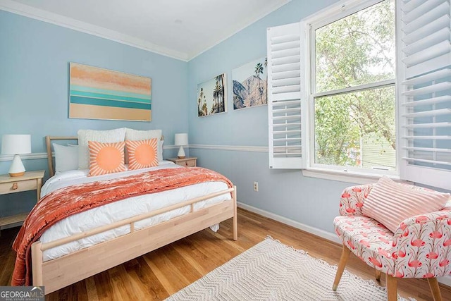 bedroom with crown molding, wood finished floors, and baseboards