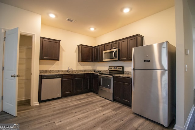 6342 Kinsland Ct, Lithonia, GA 30058 - kitchen featuring visible vents, appliances with stainless steel finishes, light wood-type flooring, dark brown cabinets, and a sink