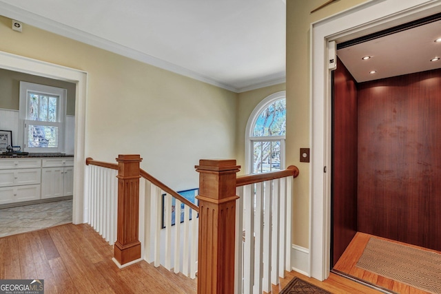 staircase with crown molding, wood finished floors, and elevator