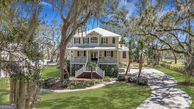 1108 E Mission Ln SE, Darien, GA 31305 - coastal inspired home featuring covered porch, driveway, stairs, a front lawn, and metal roof