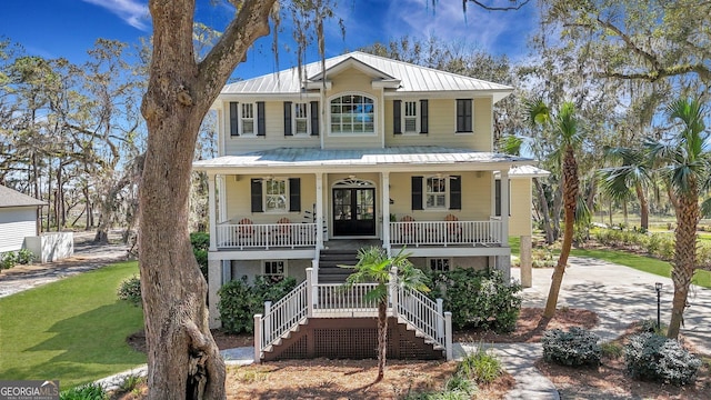 1108 E Mission Ln SE, Darien, GA 31305 - raised beach house featuring covered porch, metal roof, stairway, and concrete driveway
