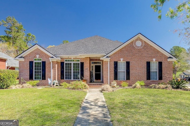 single story home featuring brick siding, roof with shingles, and a front yard