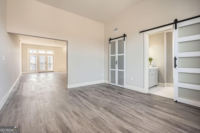interior space with a barn door, baseboards, wood finished floors, and french doors