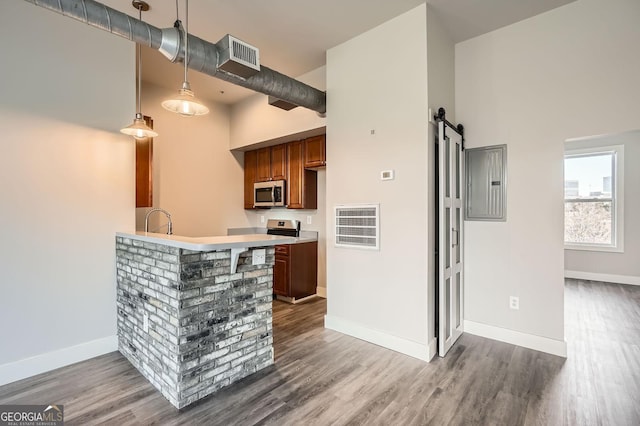 kitchen with visible vents, dark wood-type flooring, electric panel, stainless steel microwave, and a barn door