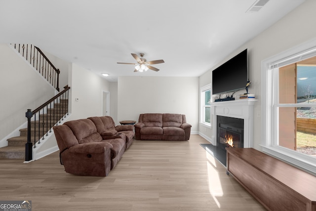 236 Village Park Dr, Newnan, GA 30265 - living area featuring stairs, light wood-type flooring, a glass covered fireplace, a ceiling fan, and baseboards