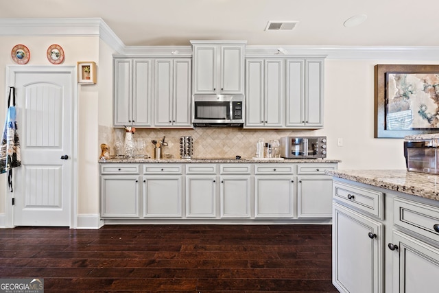 2441 Noelle Ln, Powder Springs, GA 30127 - kitchen with visible vents, stainless steel microwave, tasteful backsplash, dark wood finished floors, and crown molding