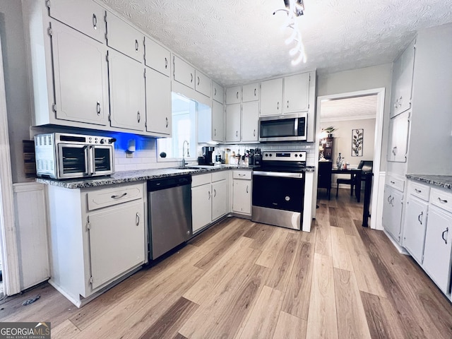 4436 Old Country Way, Snellville, GA 30039 - kitchen featuring appliances with stainless steel finishes, light wood-style floors, white cabinetry, a textured ceiling, and crown molding
