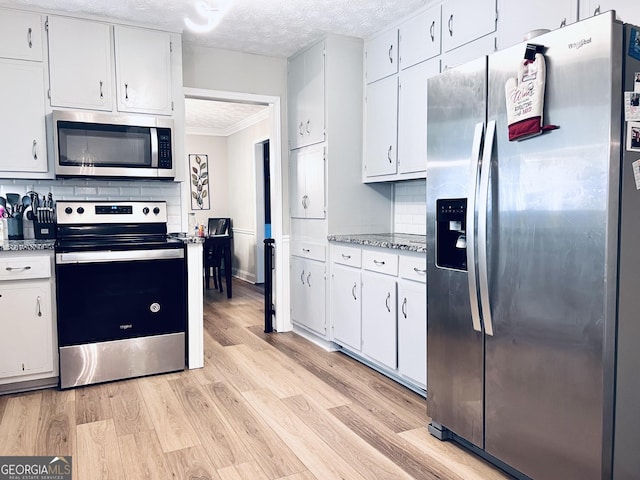 4436 Old Country Way, Snellville, GA 30039 - kitchen with stainless steel appliances, light wood finished floors, white cabinetry, ornamental molding, and a textured ceiling