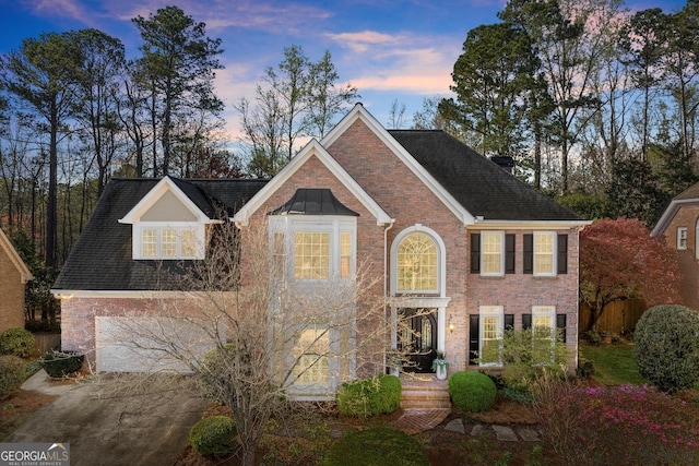 view of front facade featuring driveway, brick siding, and fence