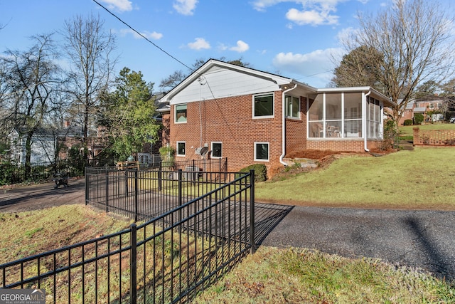 exterior space with brick siding, fence, a yard, and a sunroom