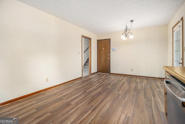 unfurnished dining area with baseboards, dark wood-style flooring, stairs, and a chandelier