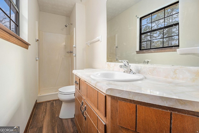 bathroom featuring toilet, a shower, vanity, and wood finished floors