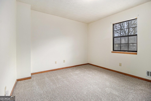 carpeted spare room featuring a textured ceiling, baseboards, and visible vents