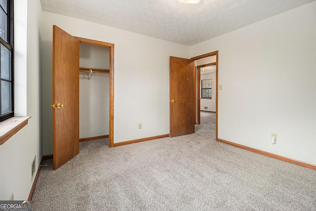 unfurnished bedroom featuring baseboards, a closet, carpet flooring, and a textured ceiling