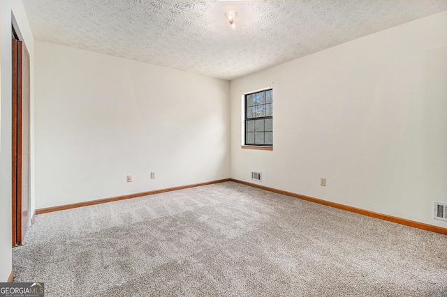 carpeted empty room with baseboards, visible vents, and a textured ceiling