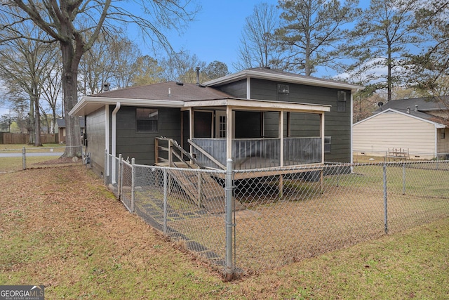 rear view of house with a sunroom, fence, and a yard