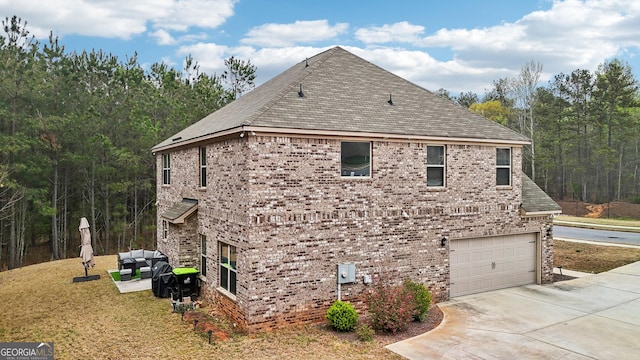 view of side of home with a garage, driveway, brick siding, and an outdoor living space