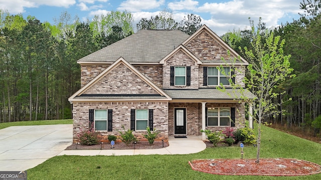 craftsman-style house with a front lawn, a porch, brick siding, and roof with shingles